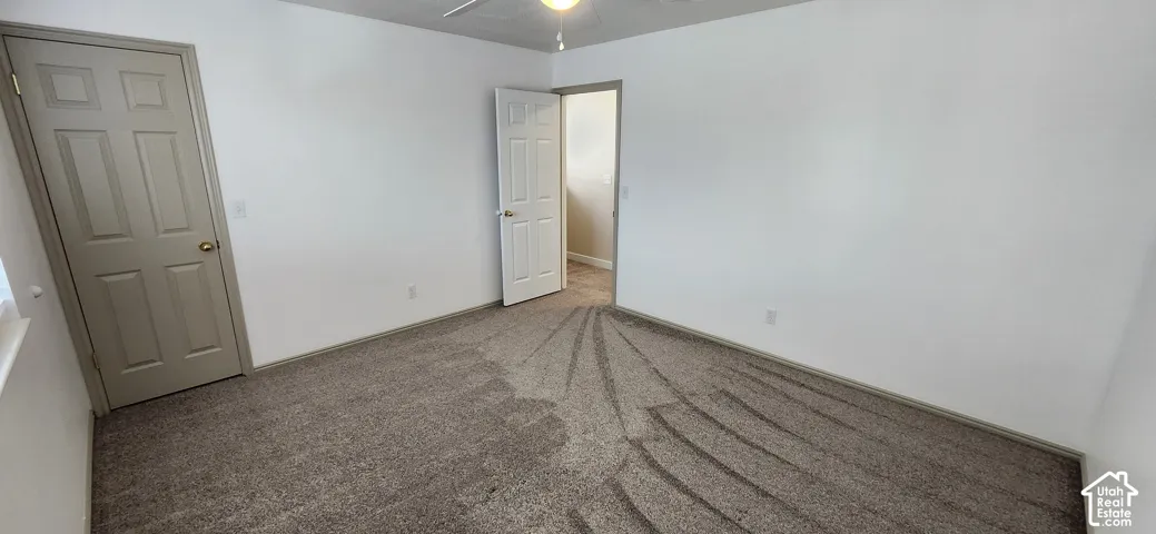 Neutral carpet flooring with light-toned walls and a ceiling fan with integrated lighting