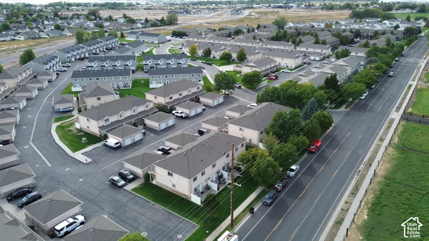 Residential neighborhood featuring multiple townhome structures and detached garages, surrounded by paved roadways and mature trees
