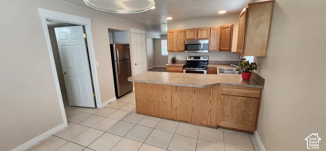 Kitchen featuring wood cabinetry, stainless steel appliances, a breakfast bar, and tile flooring
