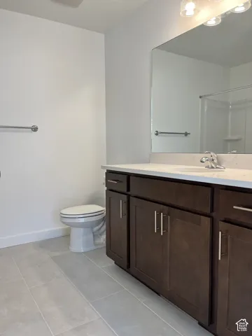 Bathroom with an elongated vanity featuring dark wood-finish cabinetry, a light-toned countertop, and an integrated mirror