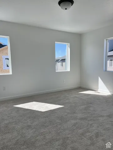 White painted walls, three windows, textured ceiling, flush mount ceiling light, and gray carpeting