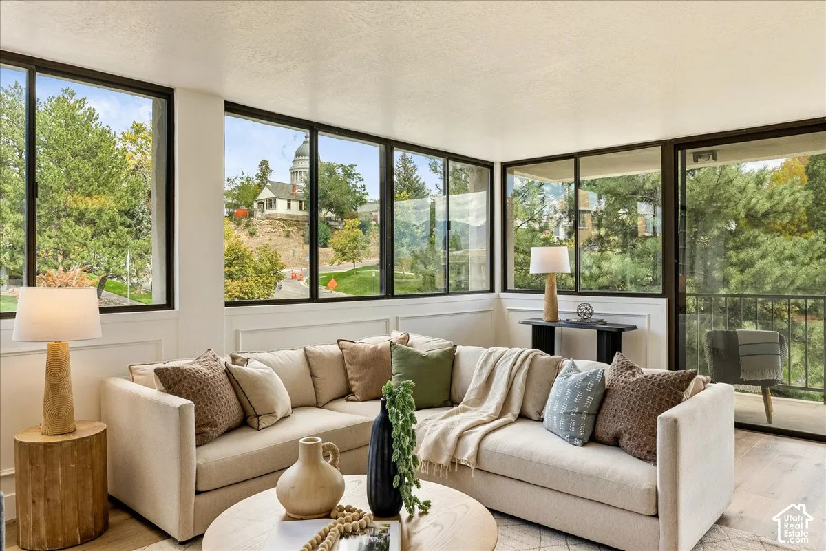 Expansive window wall, sliding glass door access to an exterior balcony, wood-finish flooring, and crisp white baseboards
