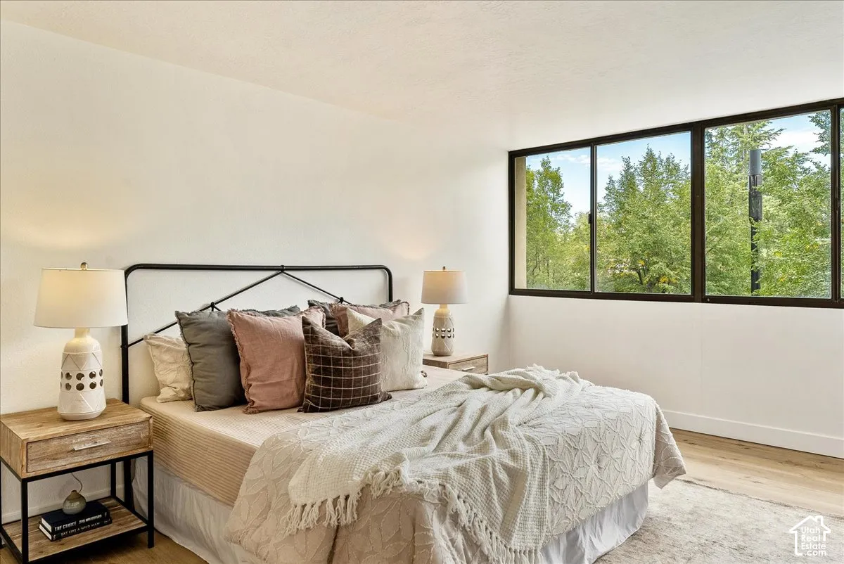 Expansive windows with dark frames, wood-finish flooring, and white walls