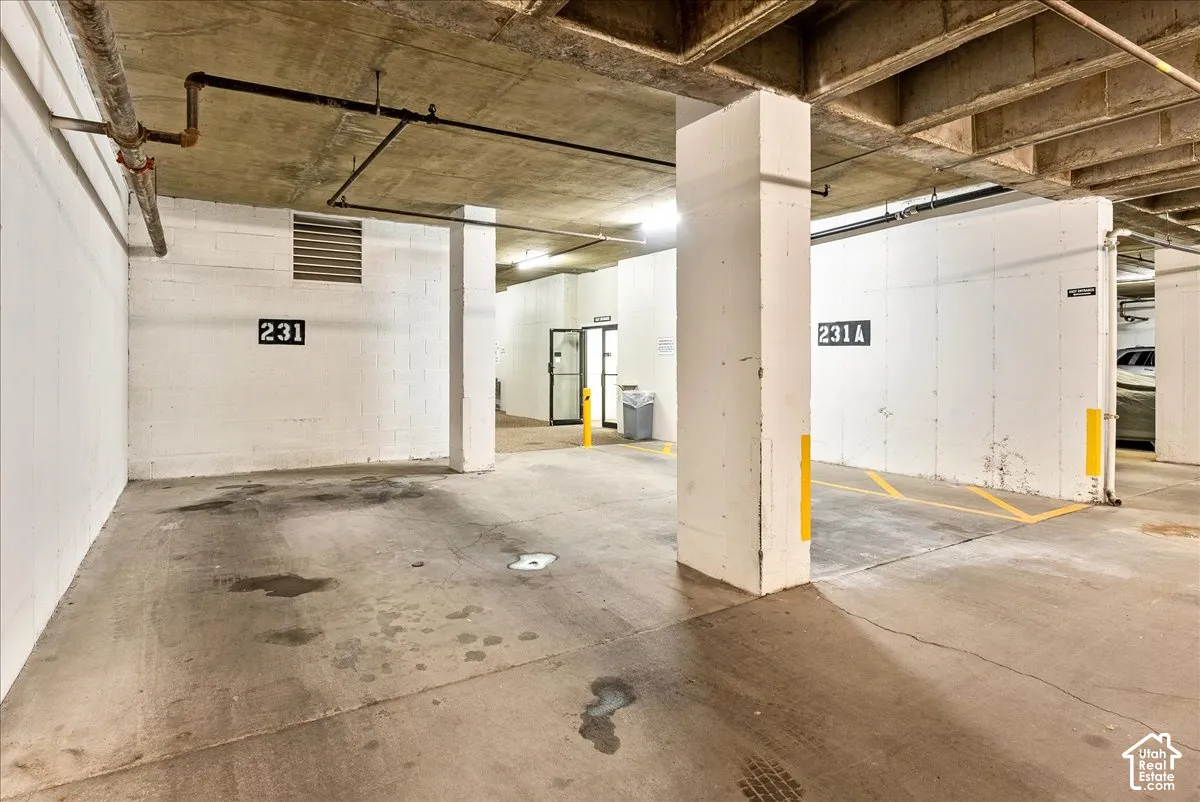 Concrete floor parking space with overhead exposed piping and concrete ceiling beams