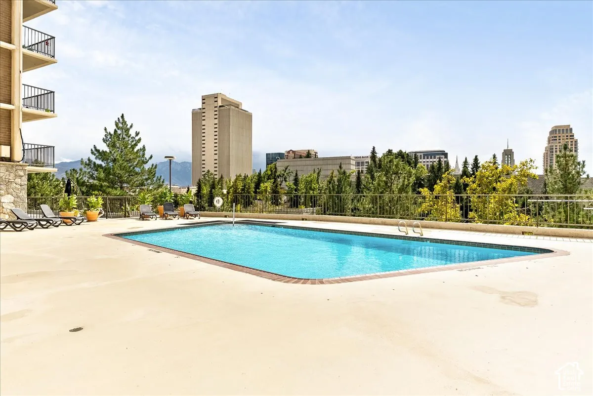 Rectangular swimming pool with a tiled edge, surrounded by a concrete deck and a metal railing