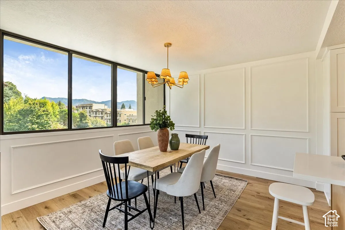 Expansive windows with dark frames, panel molding on walls, wood-finish flooring, and a chandelier lighting fixture