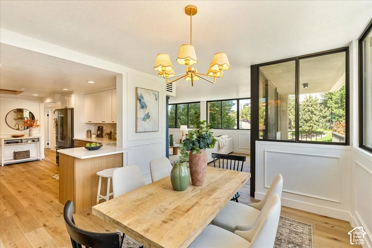 Open-concept dining area with wood-finish flooring, a contemporary chandelier, and wainscoting details