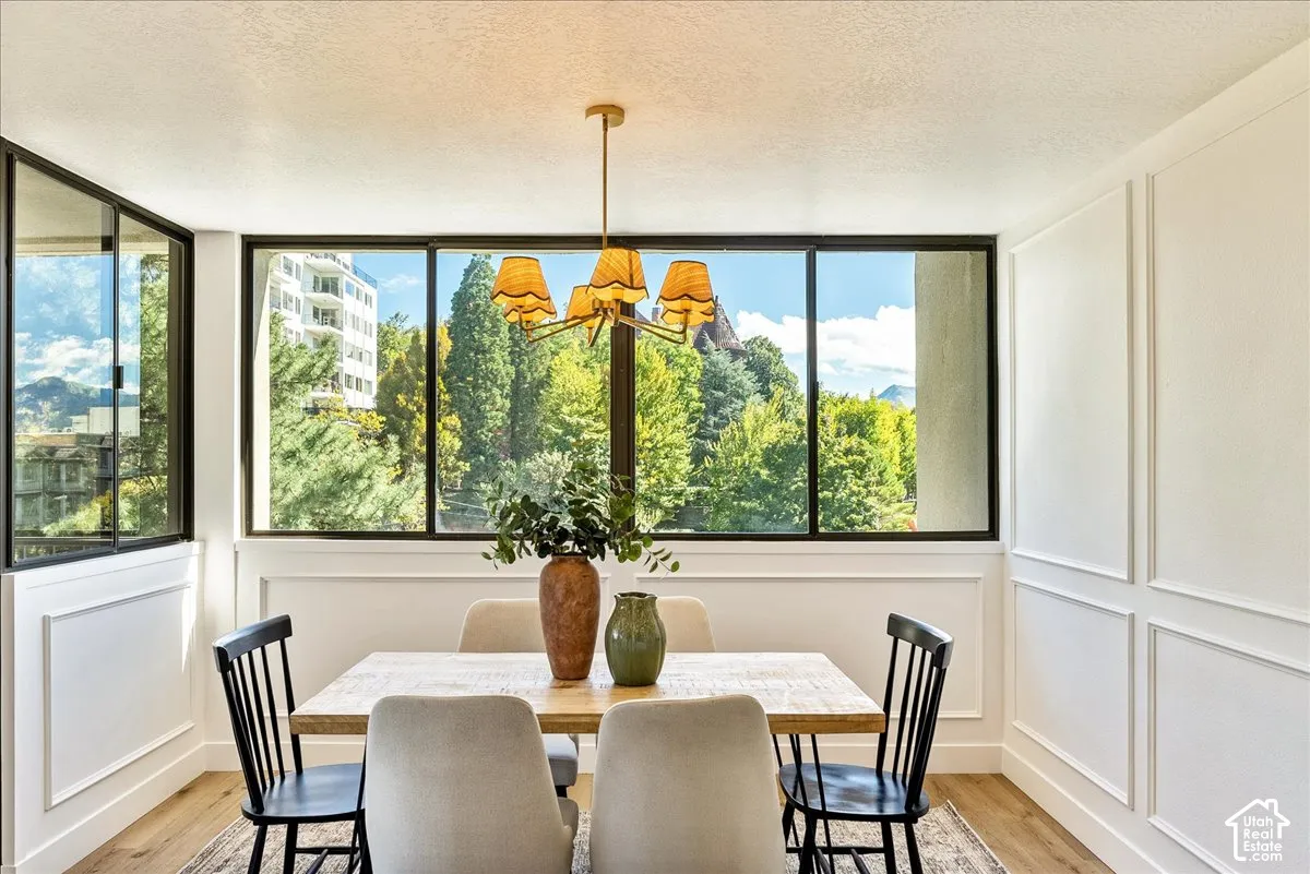 Expansive window array, decorative wall paneling, wood-finish flooring, and a brass-tone chandelier