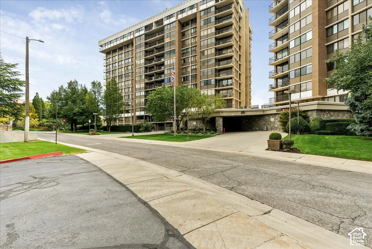 High-rise residential building with multiple balconies, a stone-clad base, and an integrated covered entrance