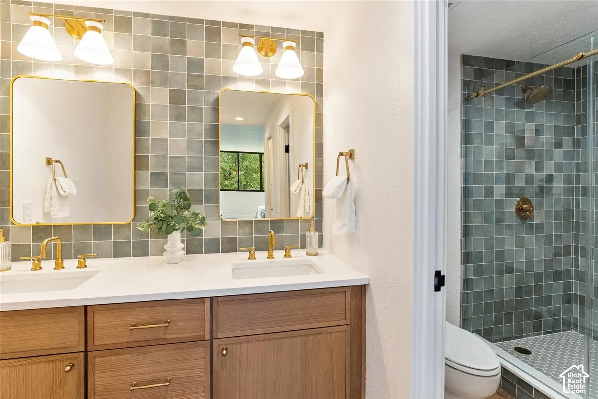 Dual vanity with wood-finish cabinetry, white countertops, and gold-tone fixtures