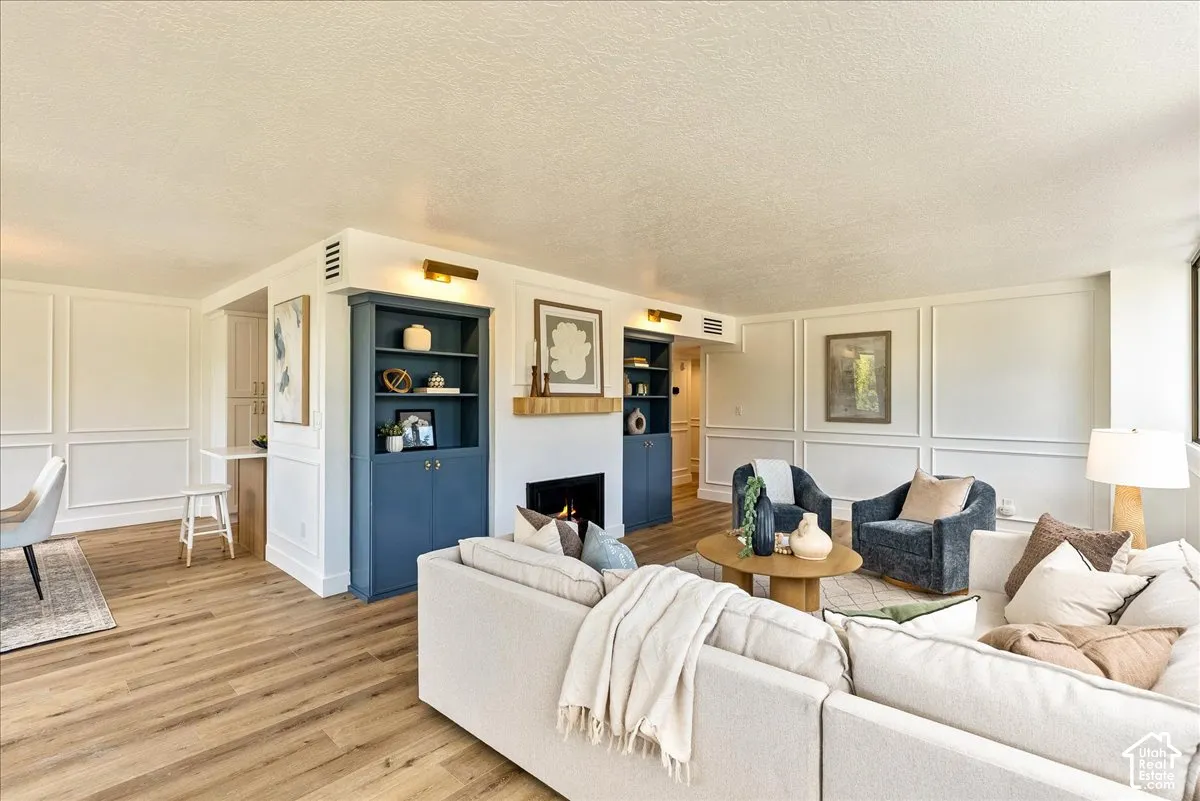 Wood-finish flooring throughout, featuring a fireplace with a wood mantel, built-in shelving, and panel molding
