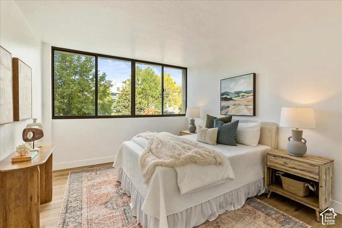 Expansive windows with dark frames, wood-finish flooring, white walls, and bright overhead lighting
