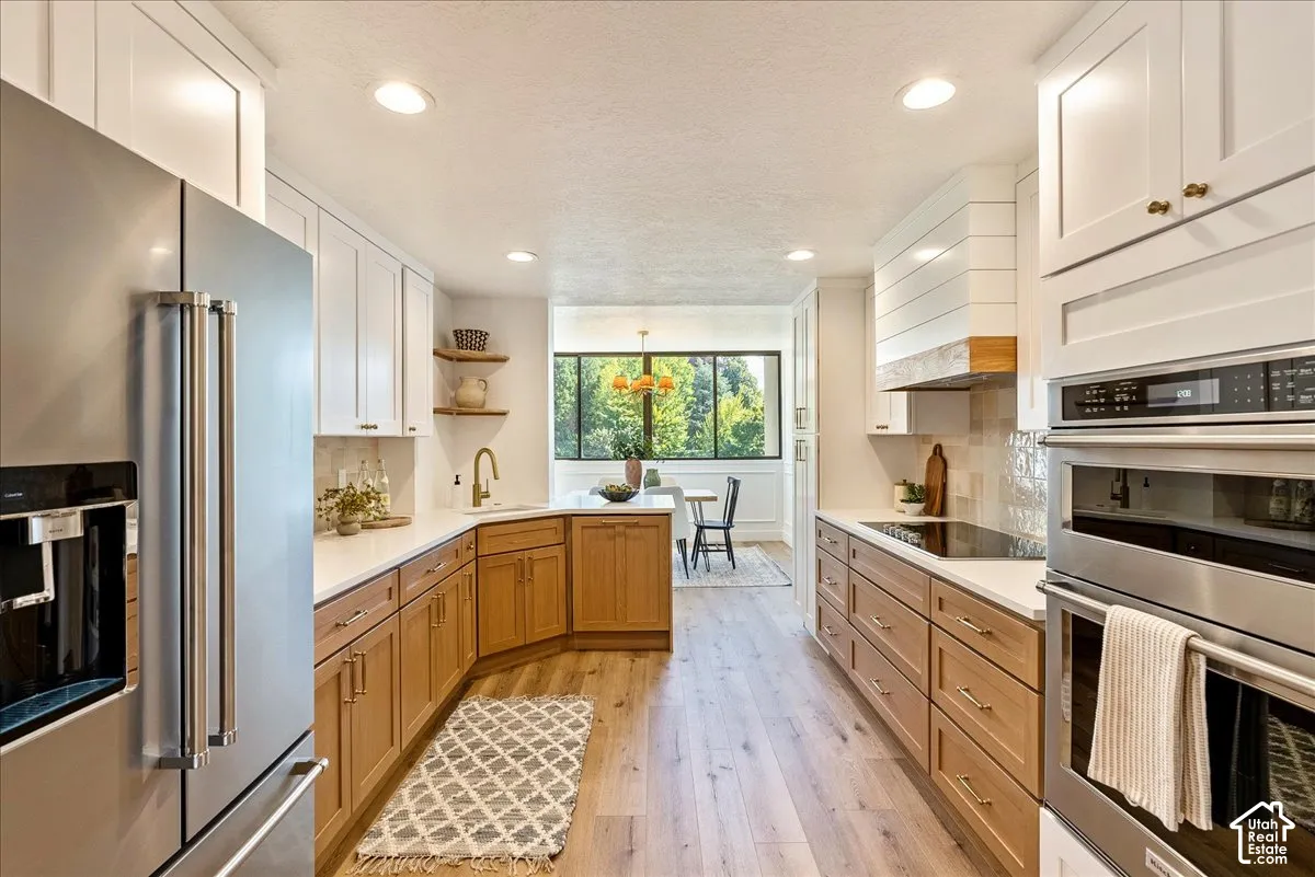 Updated kitchen featuring recessed lighting, a built-in oven, built-in microwave, wood-finish flooring, and two-tone cabinetry