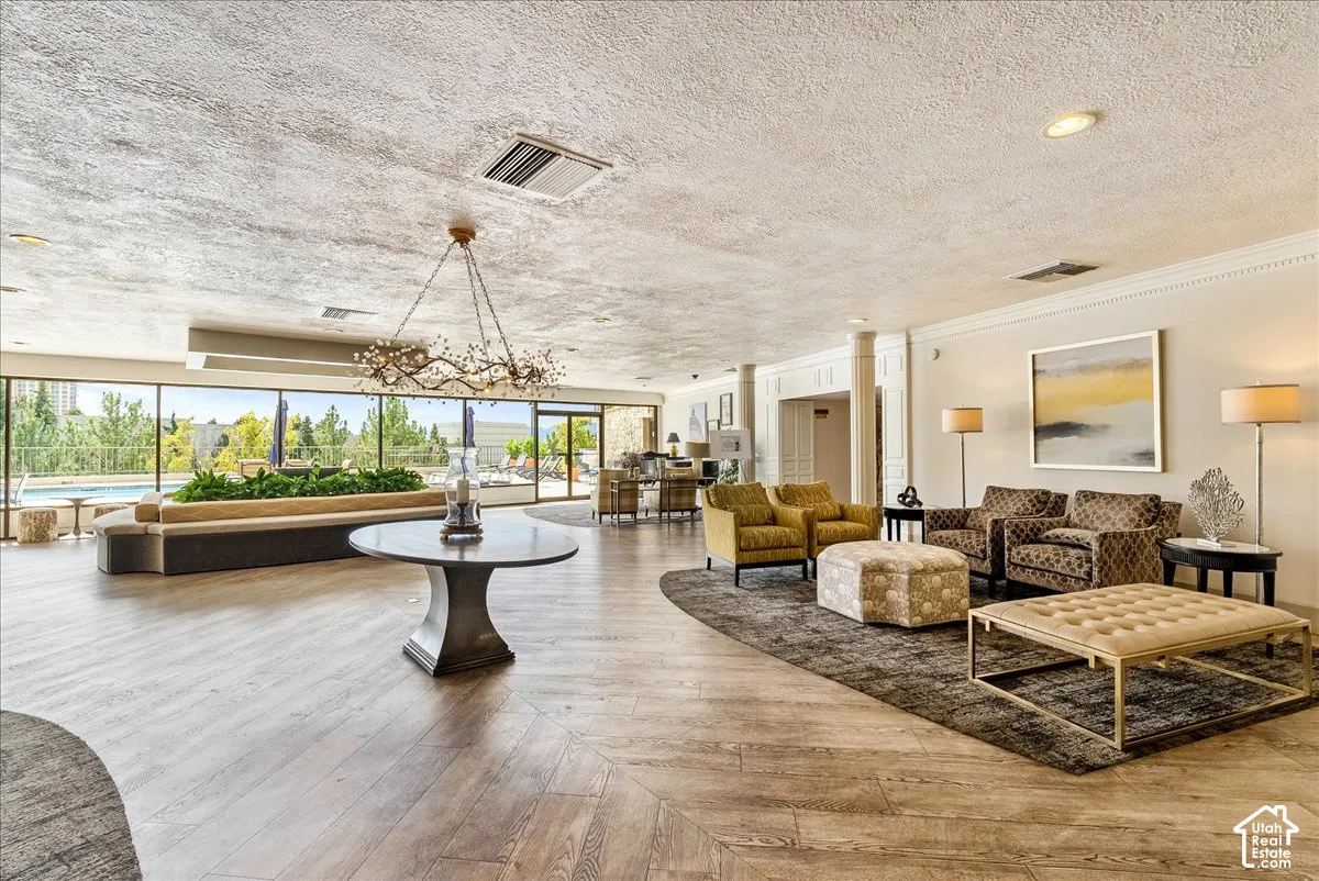 Expansive common area featuring wood-finish flooring, a decorative chandelier, and large windows