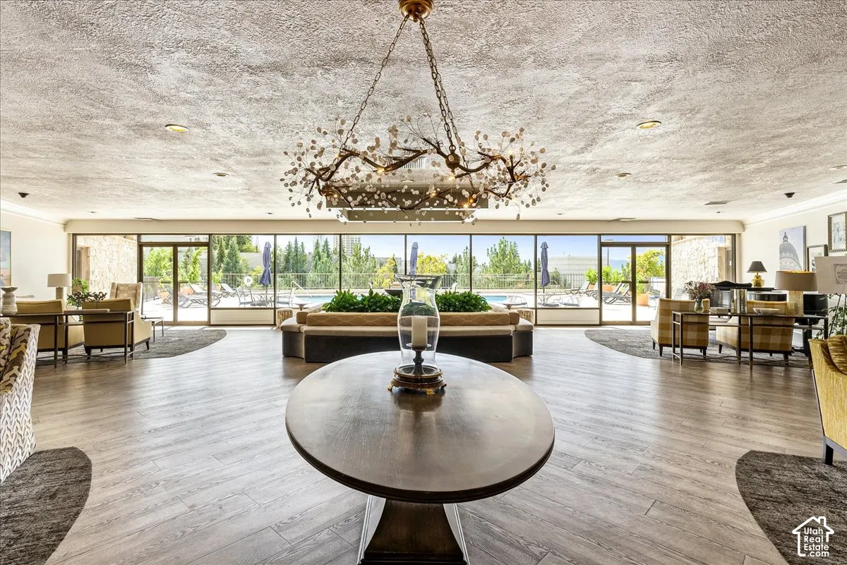 Expansive interior space with wood-finish flooring, a decorative chandelier, and full-height windows