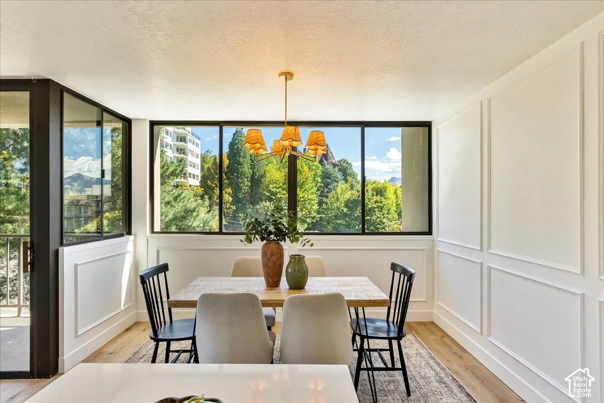 Expansive window array, wood-finish flooring, architectural paneling, and an ornamental light fixture