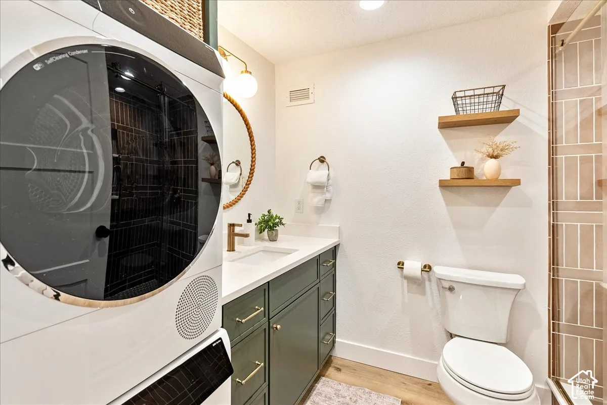 White vanity countertop with an undermount sink, dark green cabinetry with gold-tone hardware, and a wood-finish floor