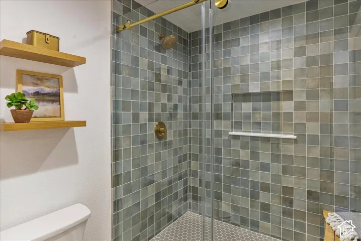 Tiled shower with glass enclosure, gold-finish fixtures, and a built-in shower niche