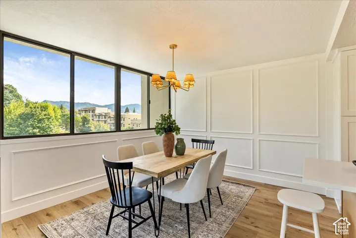 Expansive windows with dark frames, panel molding on walls, wood-finish flooring, and a chandelier lighting fixture