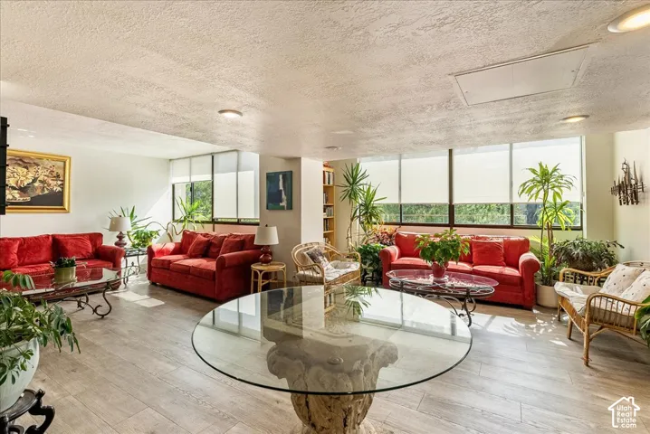 Expansive living area with wood-finish flooring, a full wall of windows, recessed lighting, and built-in shelving
