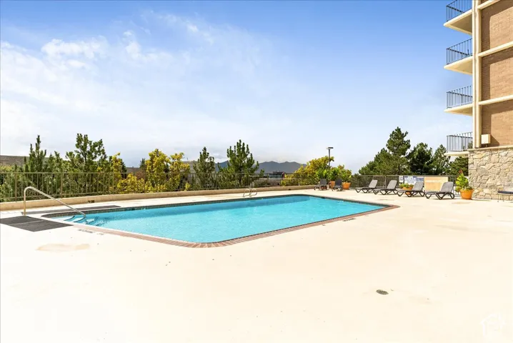 Rectangular outdoor pool with integrated steps, surrounded by a light-colored concrete deck