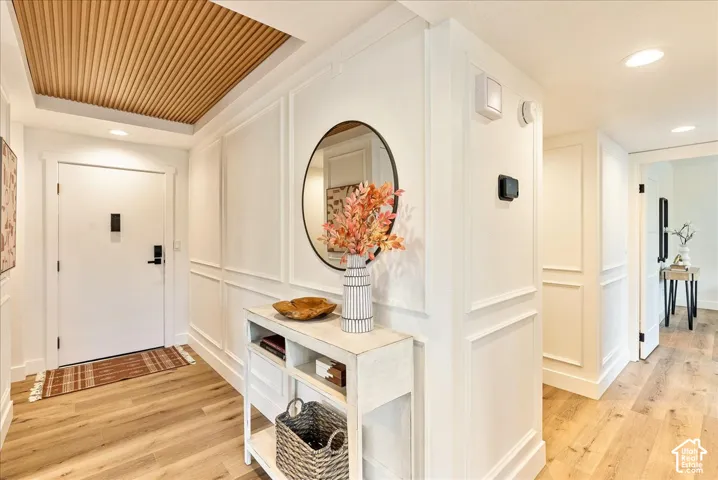 Entryway featuring wood-finish flooring, white paneling, a recessed wood-slat ceiling, and a built-in console table
