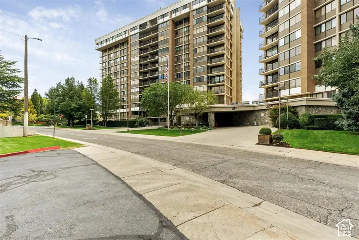 High-rise residential building with multiple balconies, a stone-clad base, and an integrated covered entrance