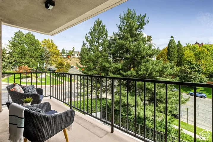 Balcony with black metal railing overlooking a tree-lined street