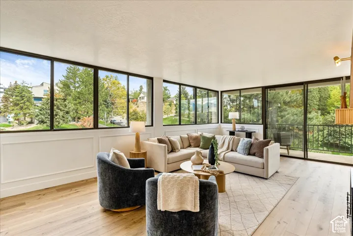 Wood-finish flooring, floor-to-ceiling windows, white paneled wall accents, and an exterior balcony with black railings