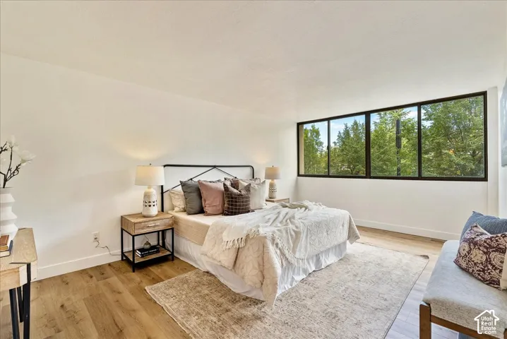 Expansive window wall with black framing, wood-finish flooring, and white walls