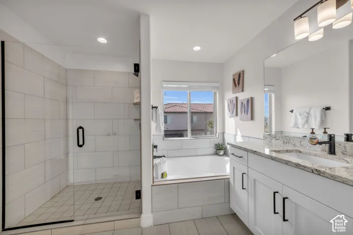 Modern bathroom featuring a glass-enclosed shower with tile surround, a built-in soaking tub, a dual vanity with granite countertop, and contemporary lighting fixtures