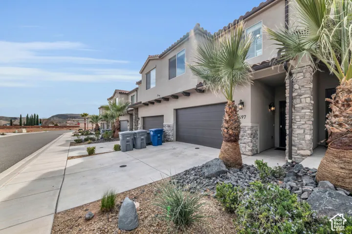 Stucco exterior with stone accents, a two-car garage, and a covered entry