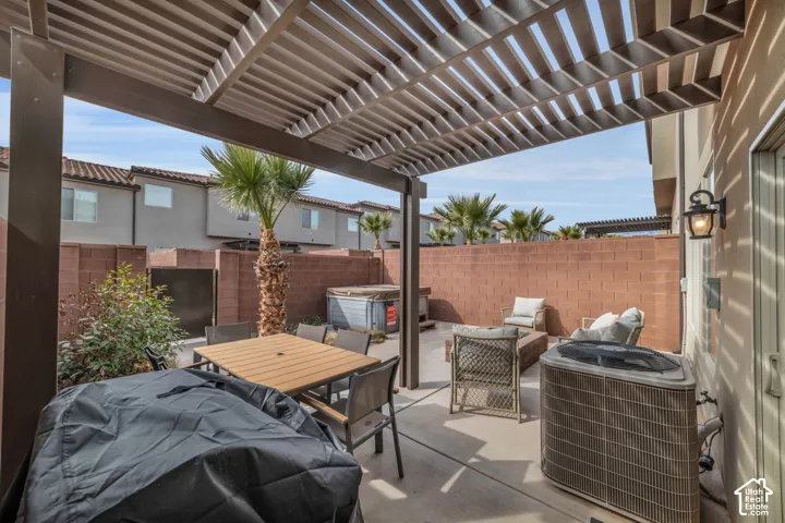 Paved patio featuring an overhead pergola structure, perimeter block wall, and integrated exterior lighting