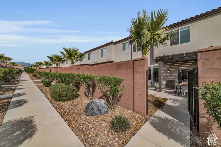 Private patio with a wood-finish pergola, concrete flooring, and an iron gate