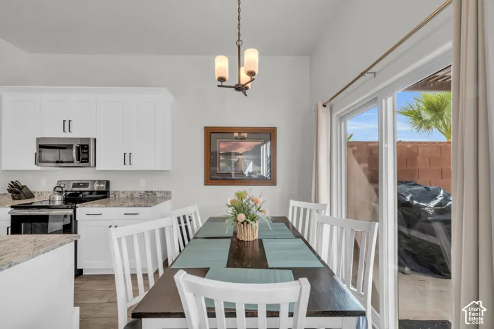 White shaker cabinetry, stainless steel appliances, granite countertops, and a sliding glass door to an outdoor area