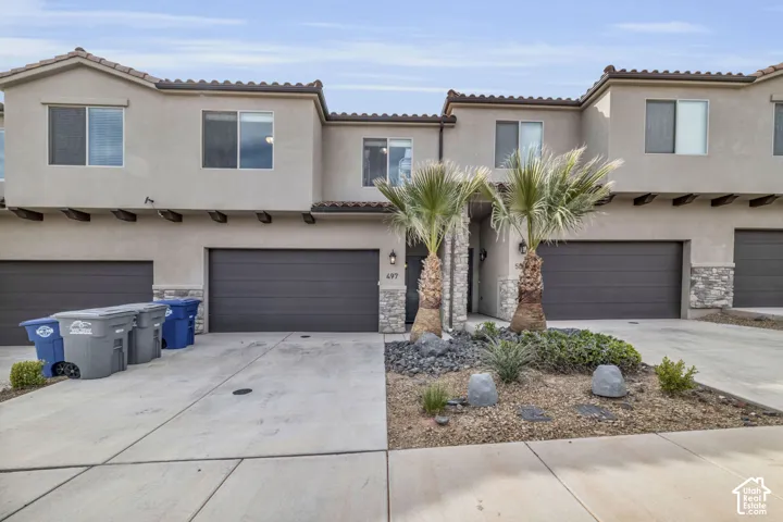 Stucco exterior with stone accents and dark garage doors
