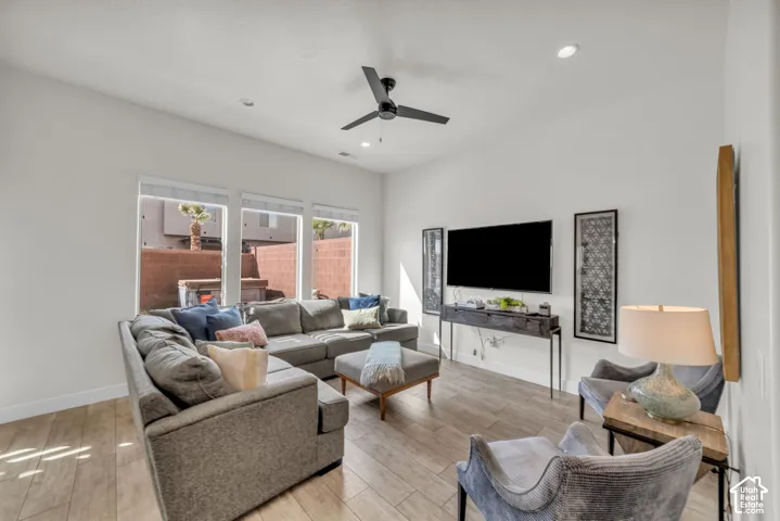 Living area featuring a ceiling fan, recessed lighting, expansive windows, wood-finish flooring, and a media console