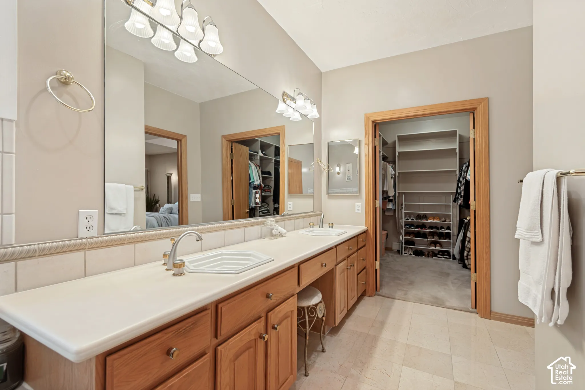 Dual vanity with integrated sinks, wood-finish cabinetry, and a large wall-mounted mirror