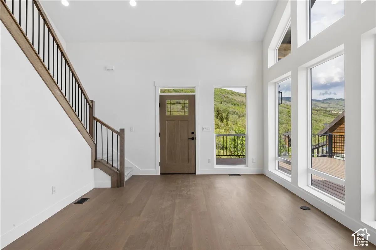 Spacious entry featuring wood-finish flooring, a contemporary staircase with dark balusters, and a solid wood entry door