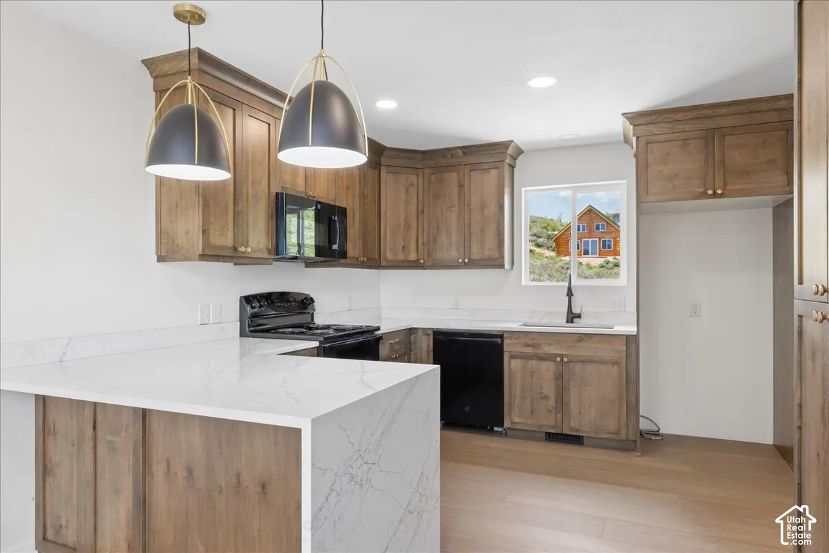 Kitchen featuring wood-finish cabinetry, quartz countertops, and black appliances