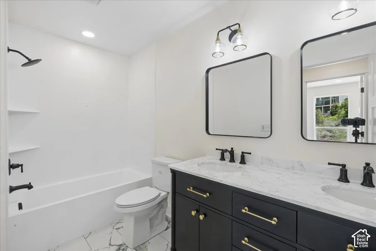 Dual sink vanity with stone countertop, matte black fixtures, and gold-finish hardware