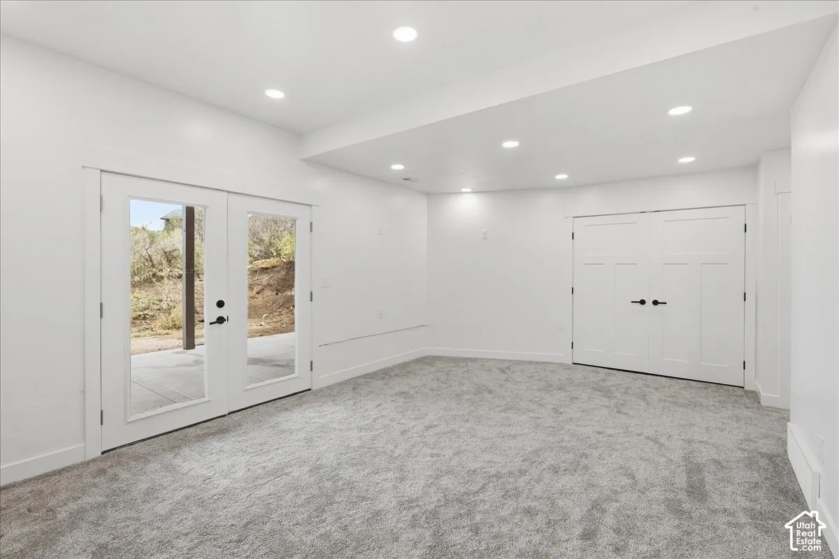 Recessed lighting, light-toned carpeting, white walls, double French doors with black hardware, and double paneled doors with black hardware