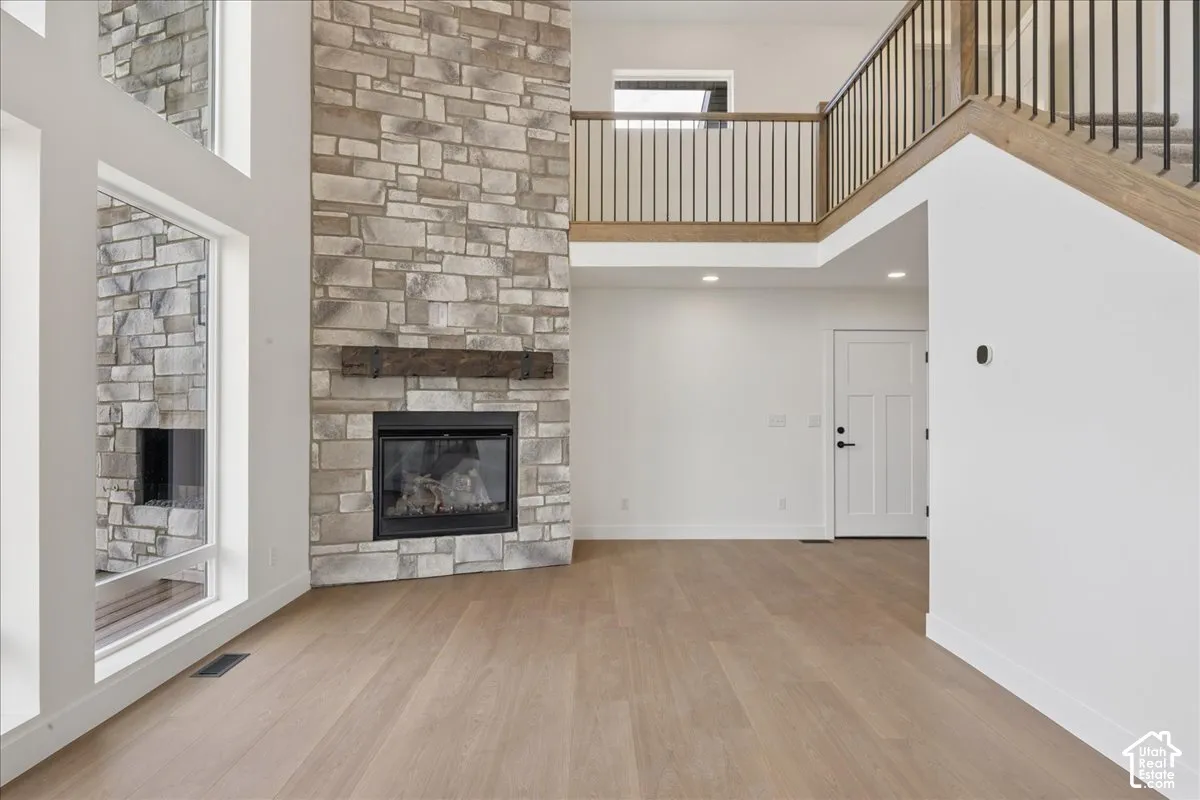 Vaulted ceilings featuring a floor-to-ceiling stone fireplace with a wood mantle