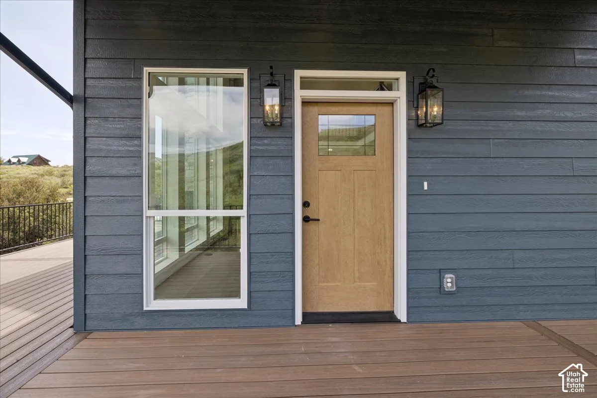 Horizontal siding with a deep blue finish, wood-finish entry door with clear glass panels, single-pane window, and two exterior wall lanterns