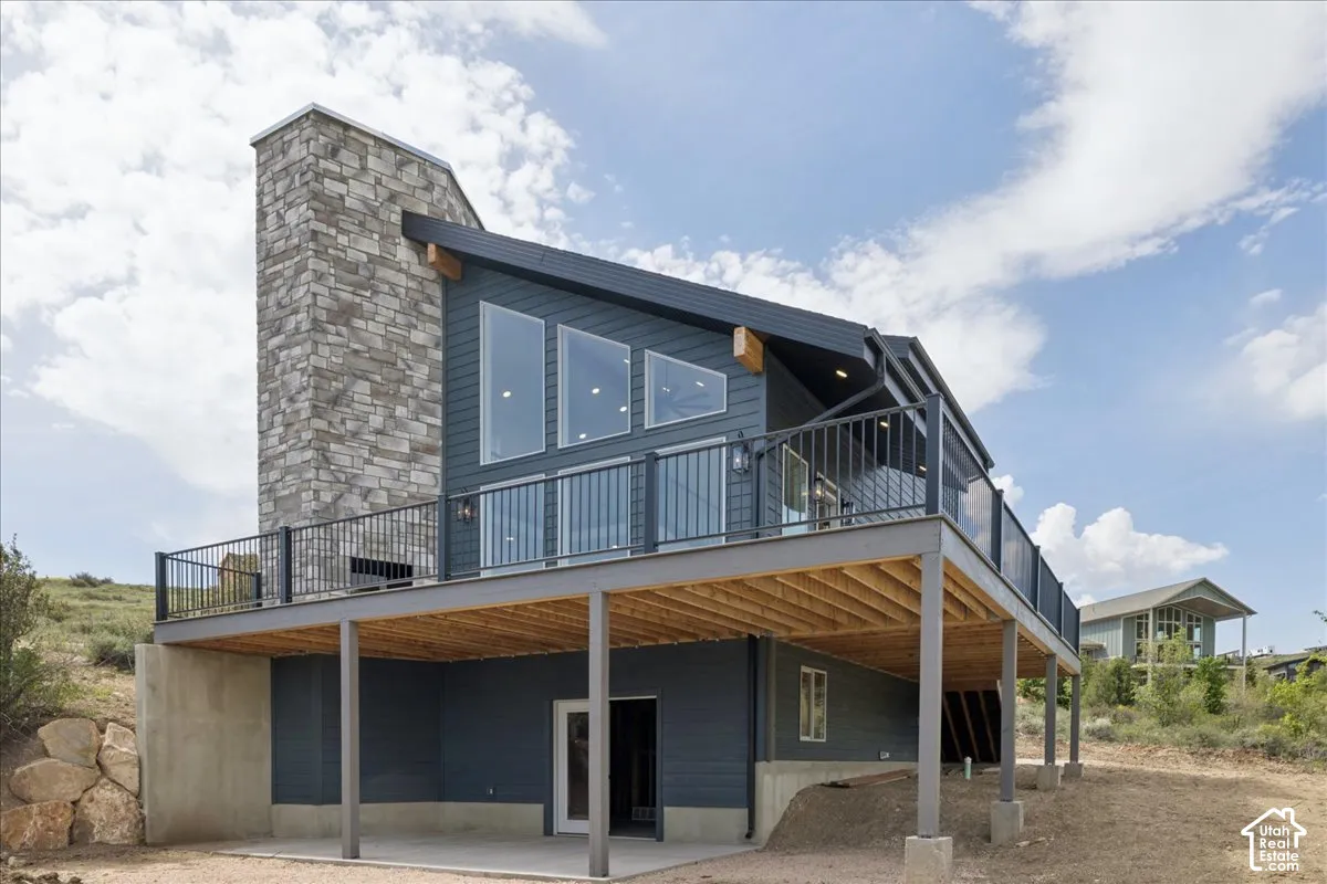 Modern architectural design featuring a stone-clad chimney and a multi-level deck