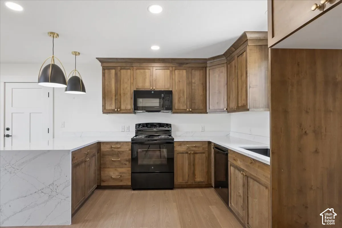 Kitchen featuring wood-finish cabinetry, quartz countertops, black appliances, and wood-finish flooring