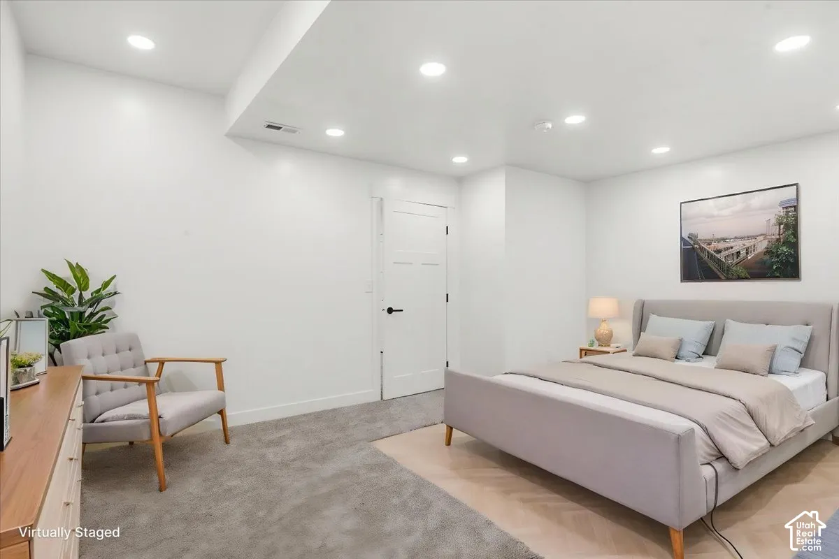 Primary Bedroom. Recessed lighting illuminating a spacious room with light-toned carpet and a white door with black hardware