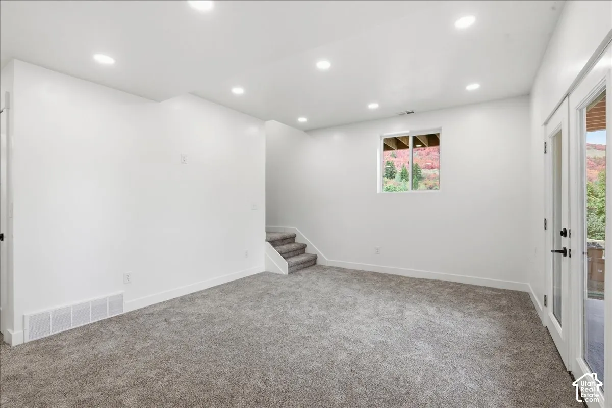 Recessed lighting, gray carpet flooring, white painted walls, a window, and double doors to access patio