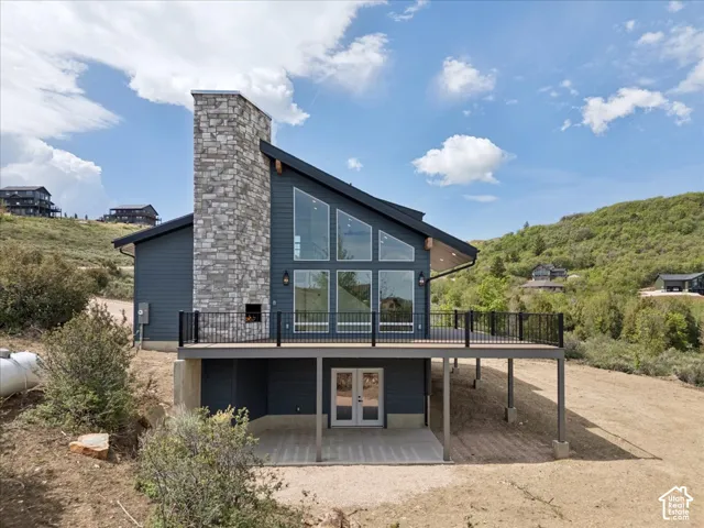 Contemporary exterior with a stone chimney, extensive deck, wall of windows, and a lower-level patio