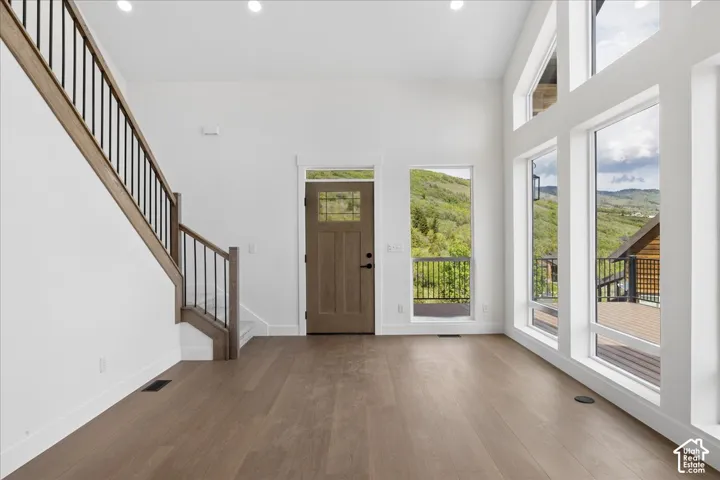 Spacious entry featuring wood-finish flooring, a contemporary staircase with dark balusters, and a solid wood entry door